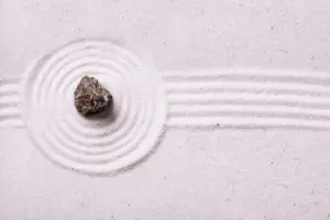 A rock sitting on top of some white sand.
